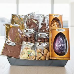 Assorted chocolate Easter eggs and treats in a box on a table with a decorative tablecloth.