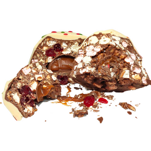 Bliss Dome cut open to reveal its filling, with a white chocolate topping and red and green decorations.