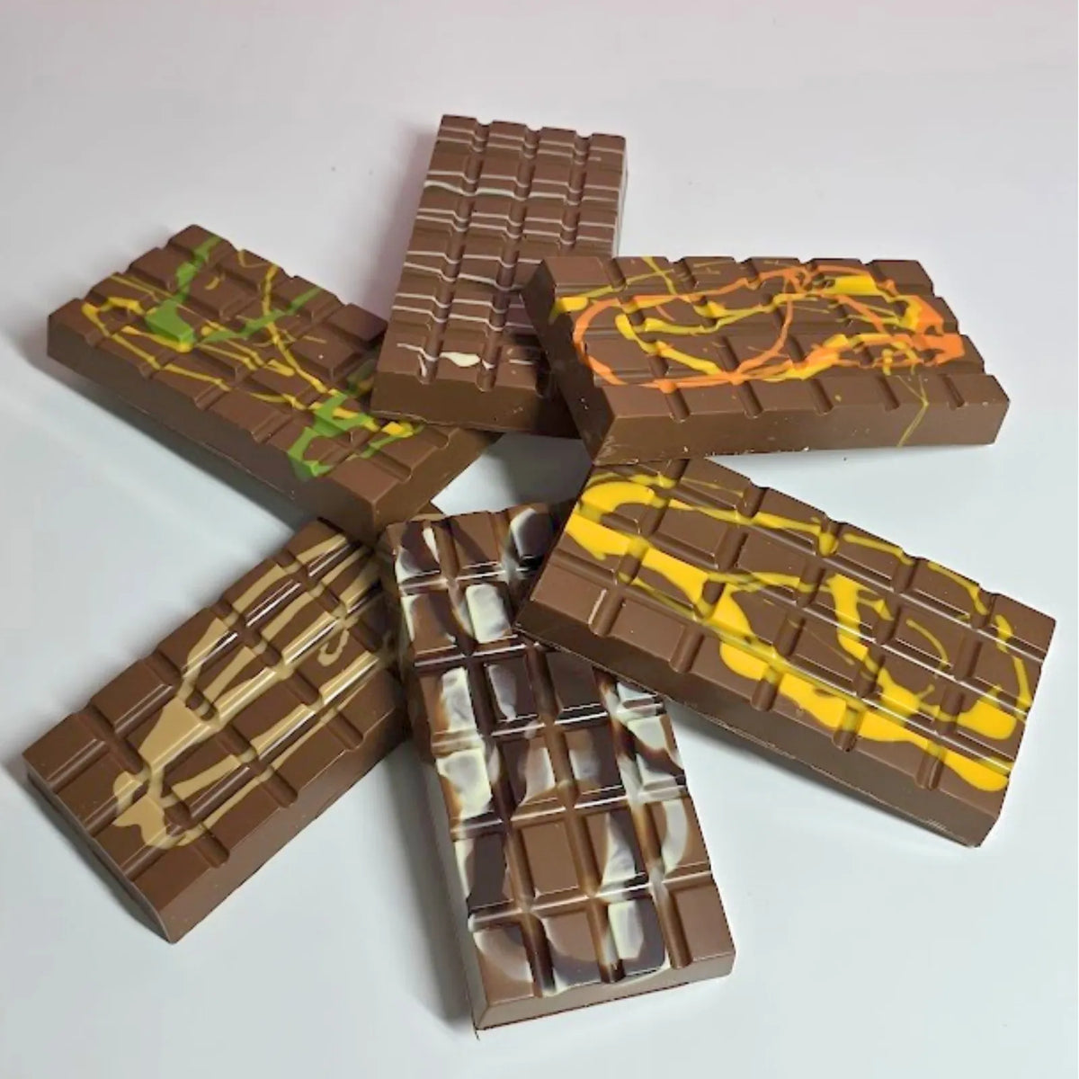 A stacked arrangement of five chocolate bars with various colorful fillings, including yellow, green, orange, and white, isolated on a white background.