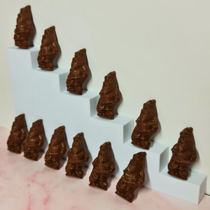 Milk chocolate Santas arranged upright and lying down around a pale blue stand.