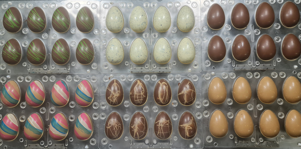 Chocolate Easter eggs in various colors and designs on a metal tray.