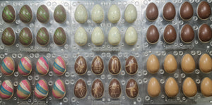 Chocolate Easter eggs in various colors and designs on a metal tray.