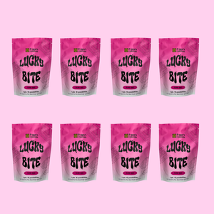 Eight pink stand-up pouches of Lucky Bite bags arranged in two rows on a solid pink background.