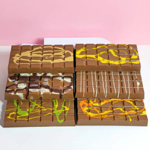 A stacked arrangement of five chocolate bars with various colorful fillings, including yellow, green, orange, and white, isolated on a white background.