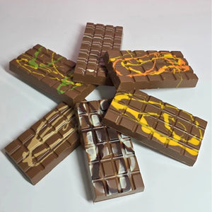 A stacked arrangement of five chocolate bars with various colorful fillings, including yellow, green, orange, and white, isolated on a white background.