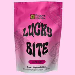 A pink stand-up pouch of Poppy's Chocolate 'Lucky Bite' blind bag, featuring black text and pink line-art illustrations of chocolate-draped pies on a light pink background.