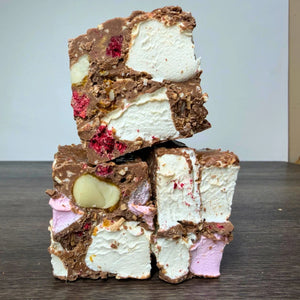 Three stacked pieces of chocolate and marshmallow frozen dessert, also known as snowball, on a dark wooden table against a light gray background.