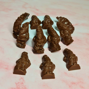 Milk chocolate Santas with salted caramel filling scattered across a pink marbled surface.