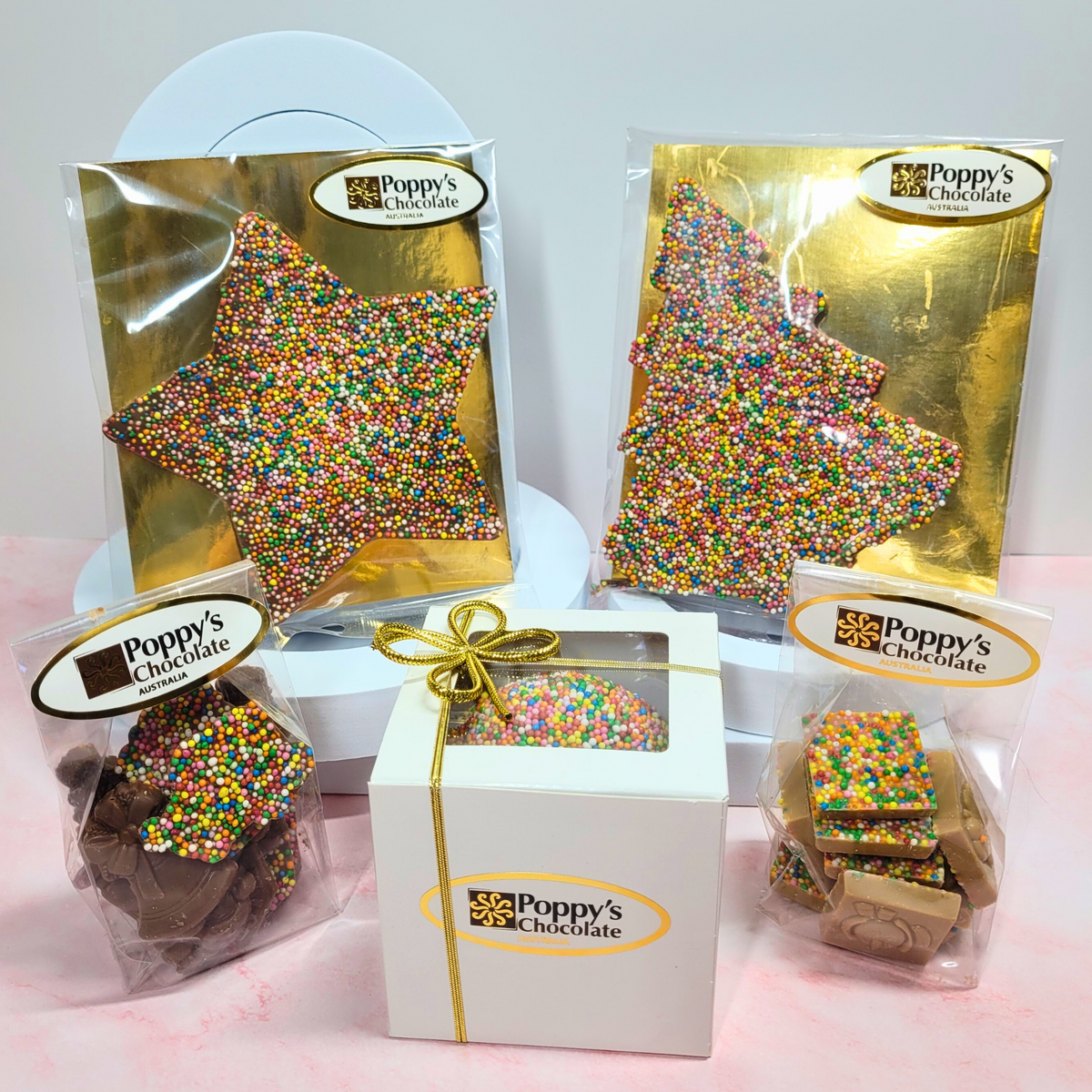 Packaged Christmas sprinkle chocolates, including a large star, Christmas tree, boxed round chocolate and two bags of smaller chocolates.