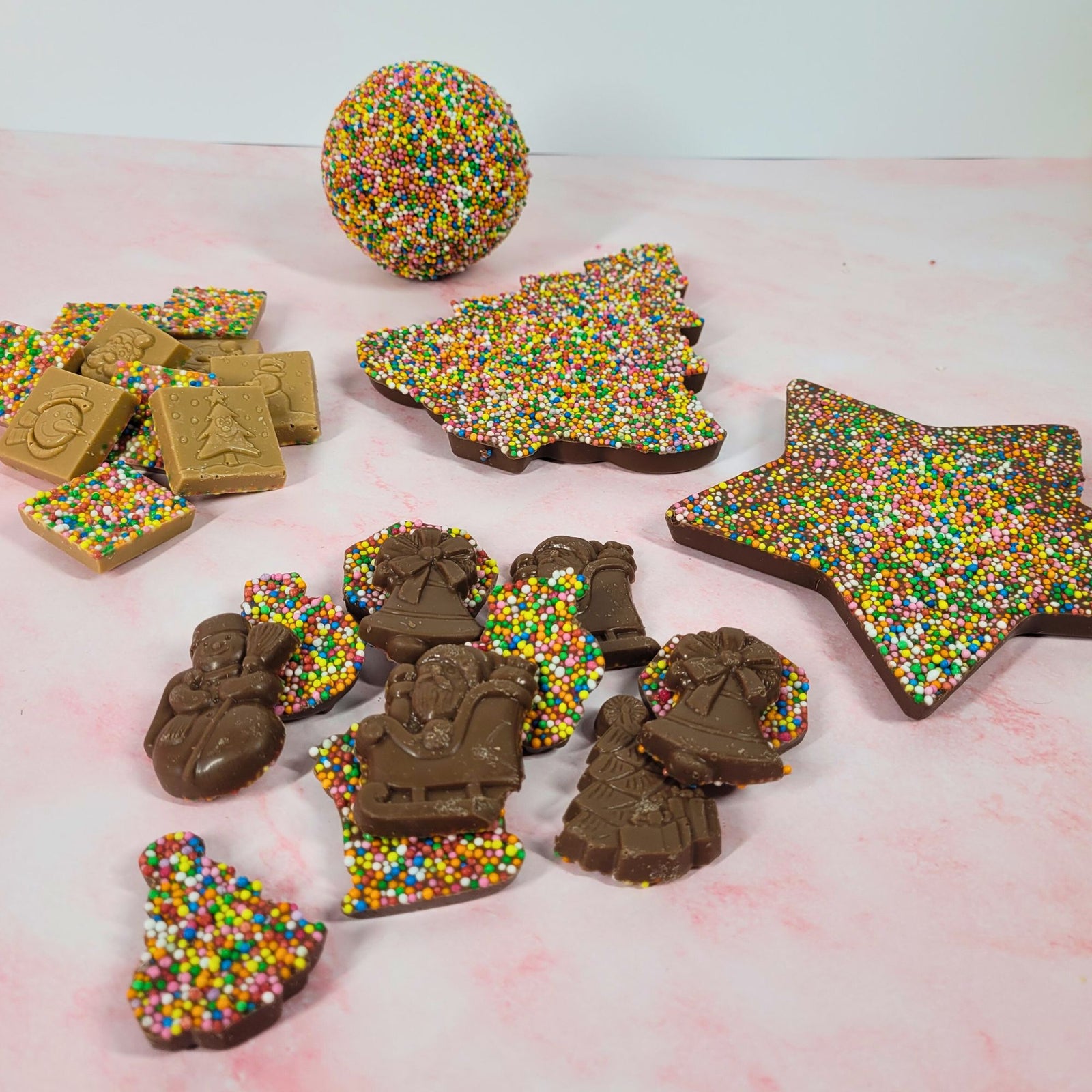 Packaged Christmas sprinkle chocolates, including a large star, Christmas tree, boxed round chocolate and two bags of smaller chocolates.