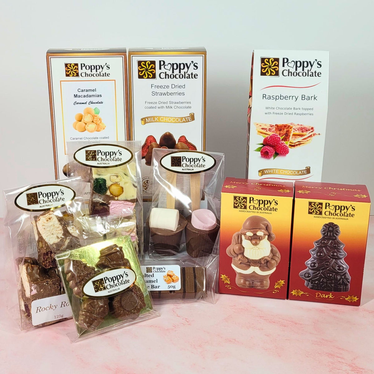 Christmas hamper contents, including caramel macadamias, chocolate-coated strawberries, raspberry bark, rocky road, Santa and Christmas tree chocolates.