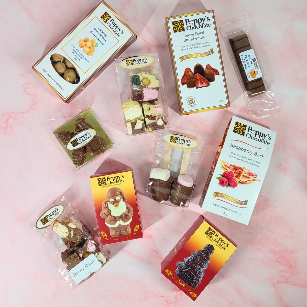 Overhead view of the packaged Christmas hamper treats arranged on a pink background.