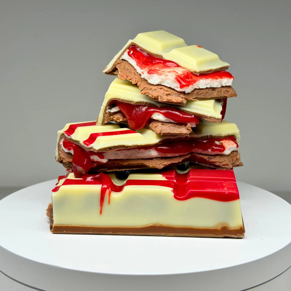 Blood Moon Bliss Block featuring a milk and white chocolate shell with red detailing, revealing layers of red salted caramel, fluffy marshmallow and raspberry milk chocolate ganache.