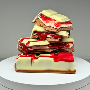 Blood Moon Bliss Block featuring a milk and white chocolate shell with red detailing, revealing layers of red salted caramel, fluffy marshmallow and raspberry milk chocolate ganache.