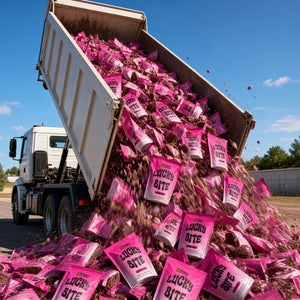 A white dump truck is shown outdoors with its bed open, pouring many bright pink bags labeled 'LUCKY BITE' over loose brown material under a blue sky.