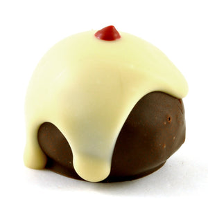Mini chocolate-coated pudding topped with white chocolate and a small red decoration.